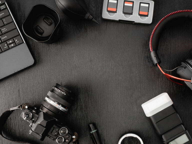 top view of work space photographer with digital camera, flash, cleaning kit, memory card, external harddisk, USB card reader, laptop and camera accessory on black table background